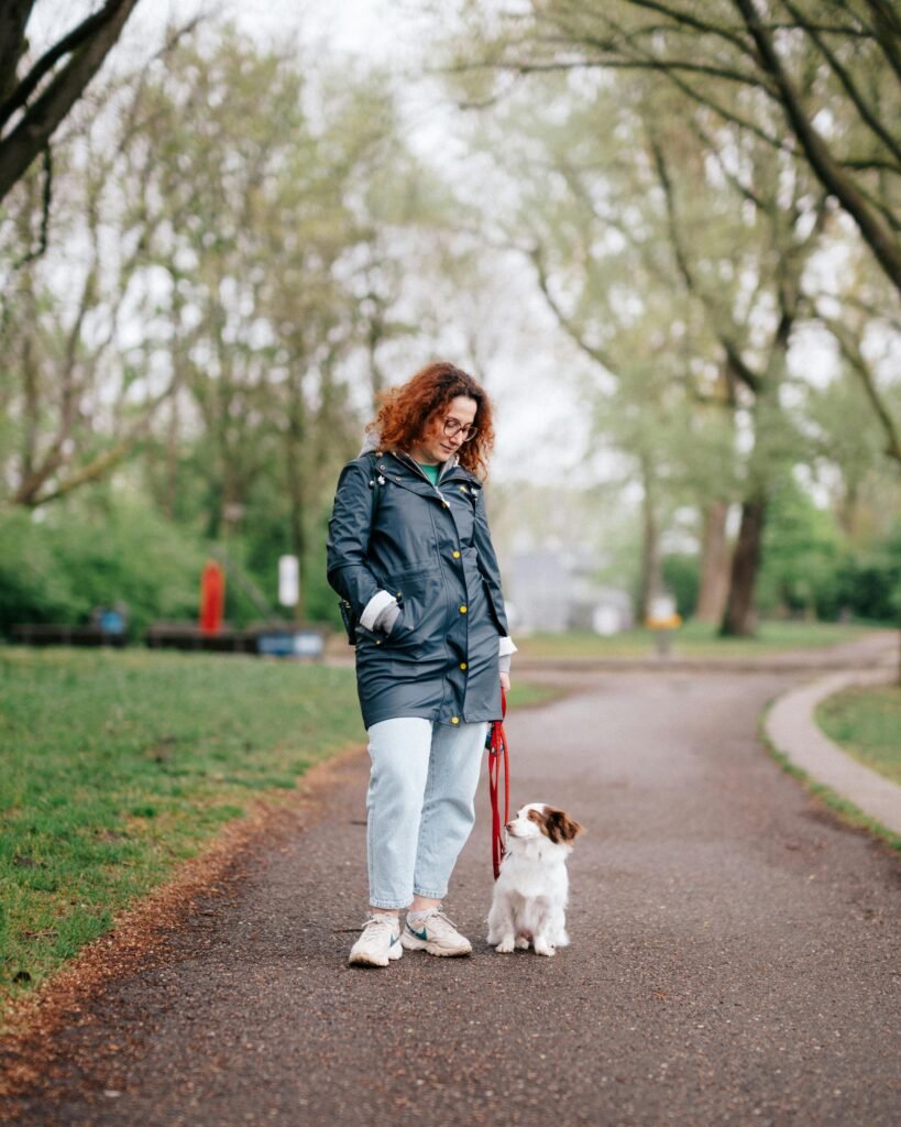 Woman with dog on a sunny day walk through a green park pathway.
